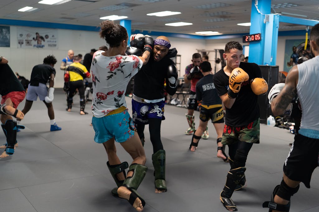 Group of athletes training in a boxing gym with focus on kicking techniques.